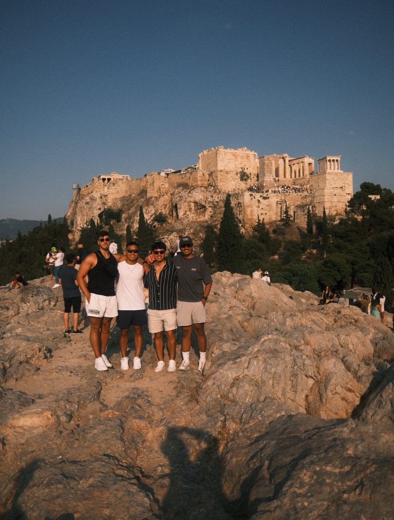 4 students posing at cliffside beach at sunset
