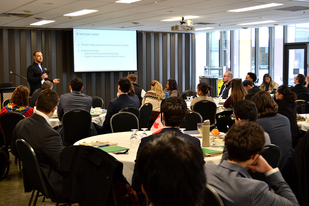 Man presenting with microphone to a large, attentive audience at the CUSC conference. Projector displays "AI and your career".