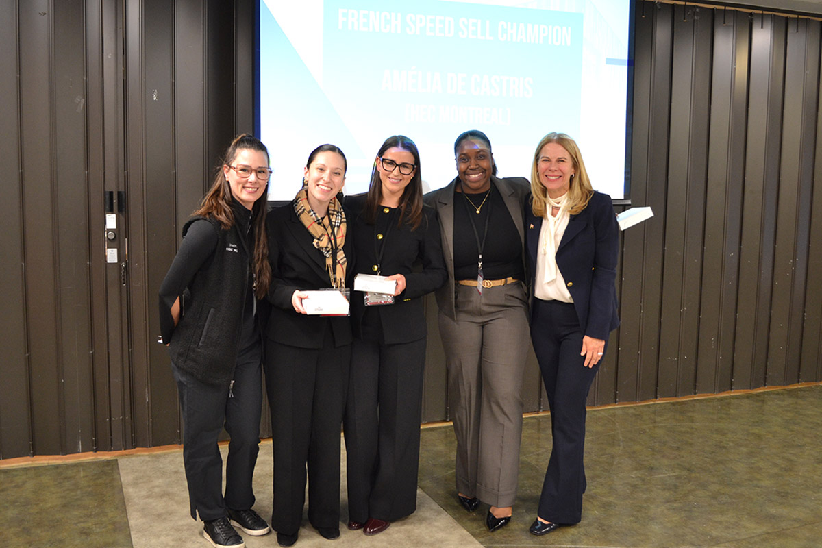 Karen Peesker posing with other four women, smiling, in front of a screen displaying "French Speed Sell Champion." Two hold awards, celebrating at the SCUC Conference.