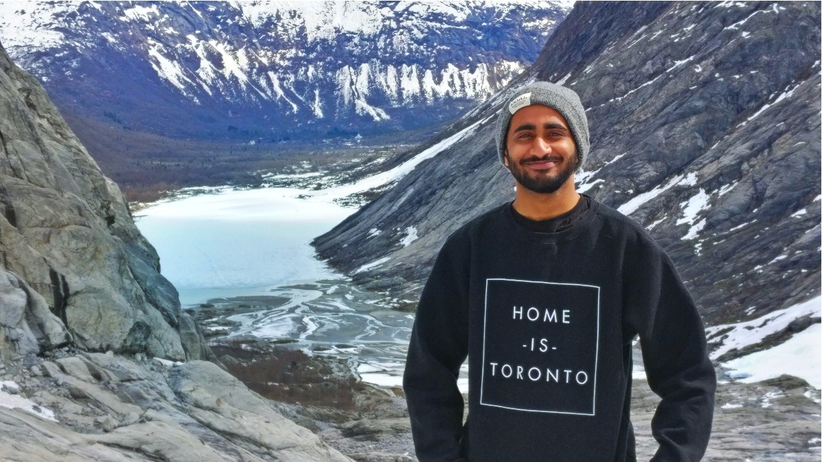 Happy torontonian standing in front of a scenic background with mountains and a river