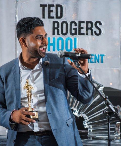 A young male student happily giving his speech after receiving his trophy at an awards ceremony