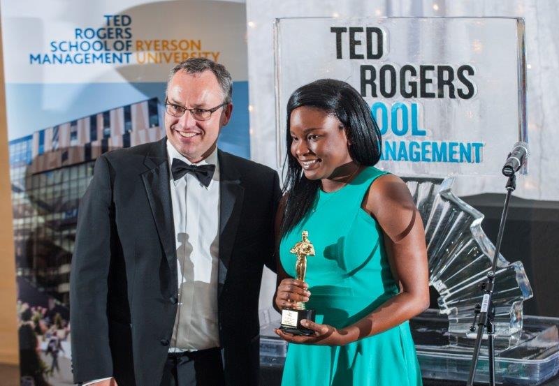 Dean posing with a young female student while she holds a trophy at an awards night