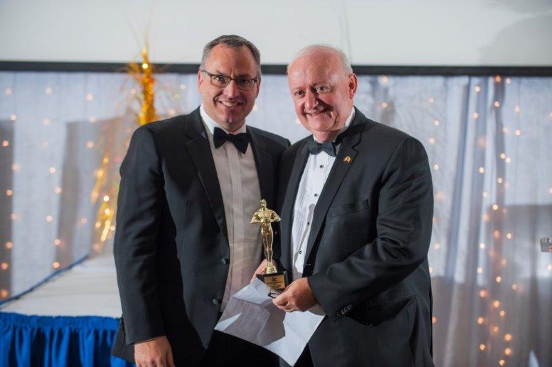Dean posing with an older man with his new trophy  at a TRSM awards ceremony