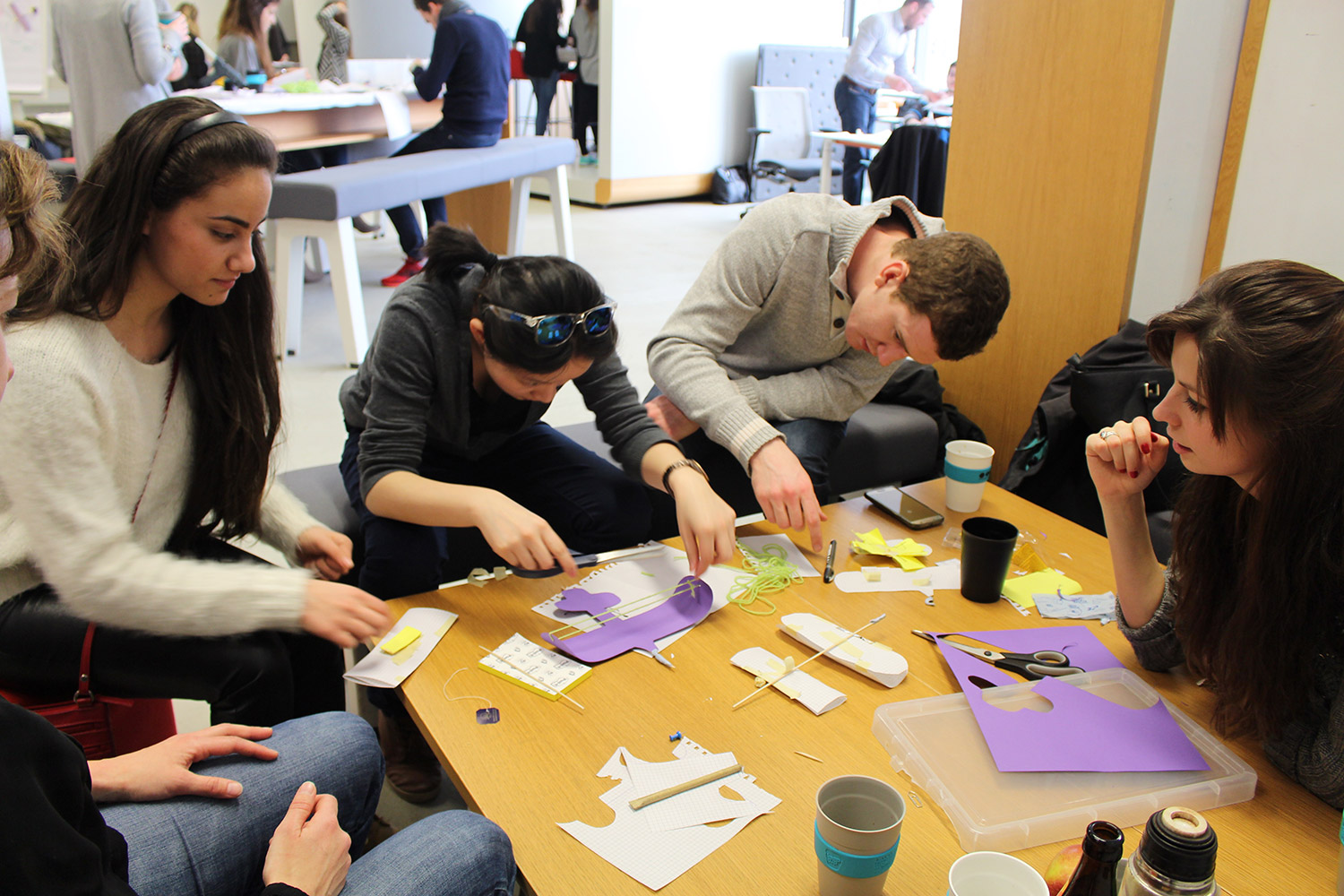 Group of students gathered around a table and working on prototyping