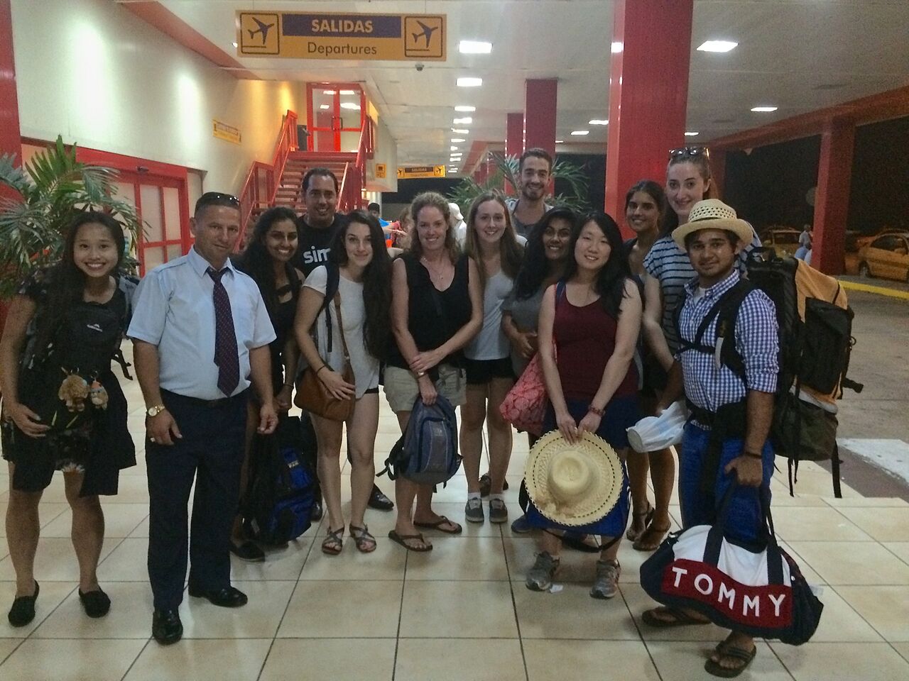 A group of students and faculty members posing at an airport in Trinidad