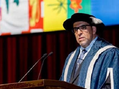 Lachemi standing a podium talking to a sea of graduating students