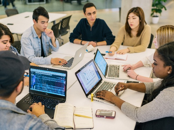 A group of young adults in a brainstorming session on their laptops