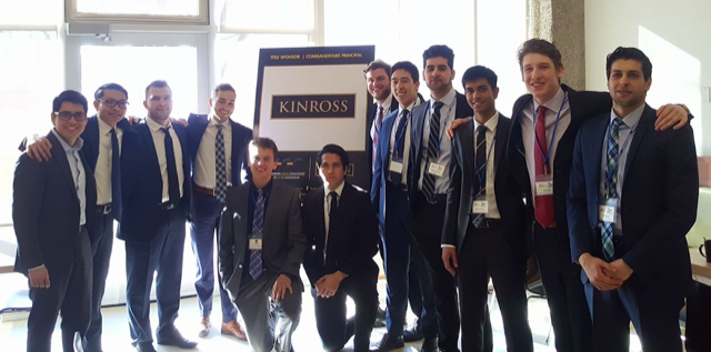 a large group of happy second place winners pose in front of a Kinross banner 
