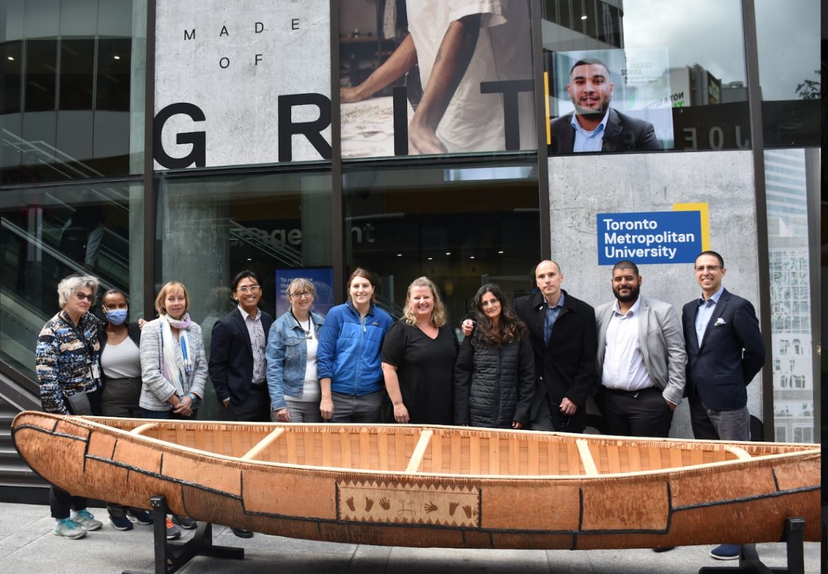 TRSM members with birch bark canoe in front of school building
