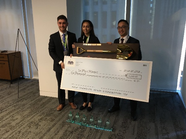 3 happy case competition winners pose with a giant cheque and a golden shovel