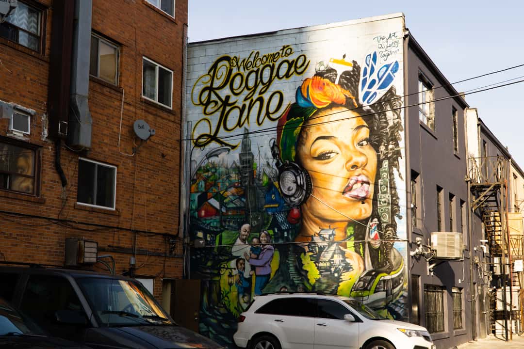 The Reggae Lane mural (Portrait of Black woman surrounded by greenery and community) sits at Eglinton West and Oakwood Avenue