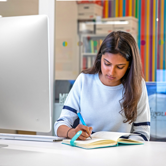 Student taking notes at a computer