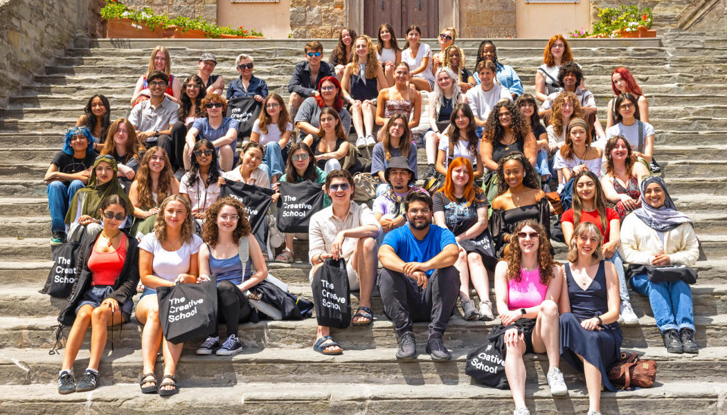 Students smiling seating in the steps of a concrete staircase in Cortona, Italy