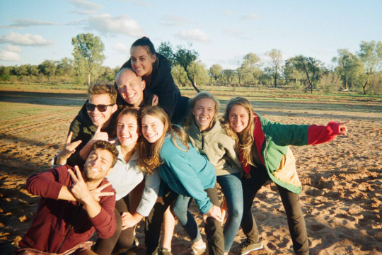 Students smiling seating in the steps of a concrete staircase in Cortona, Italy