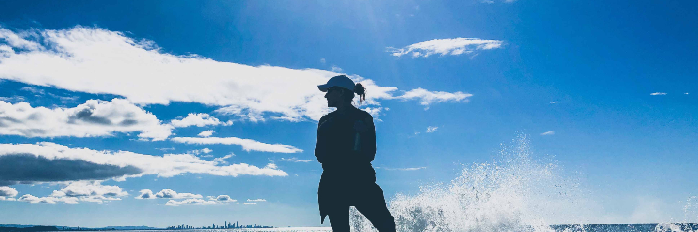 Four students smiling and holding a Canadian flag with mountains in the background