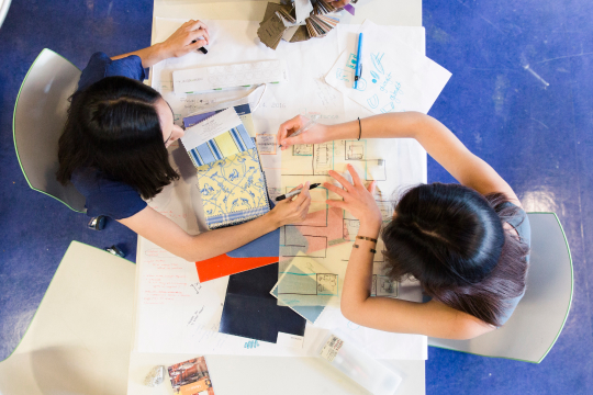 Two students reviewing materials and sketches