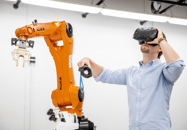 Person using a VR headset and a small Kuka robot