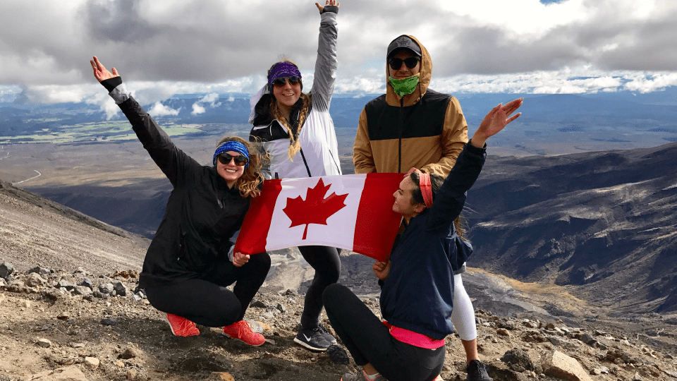 Four The Creative School students in winter clothing holding Canadian flag in exchange program