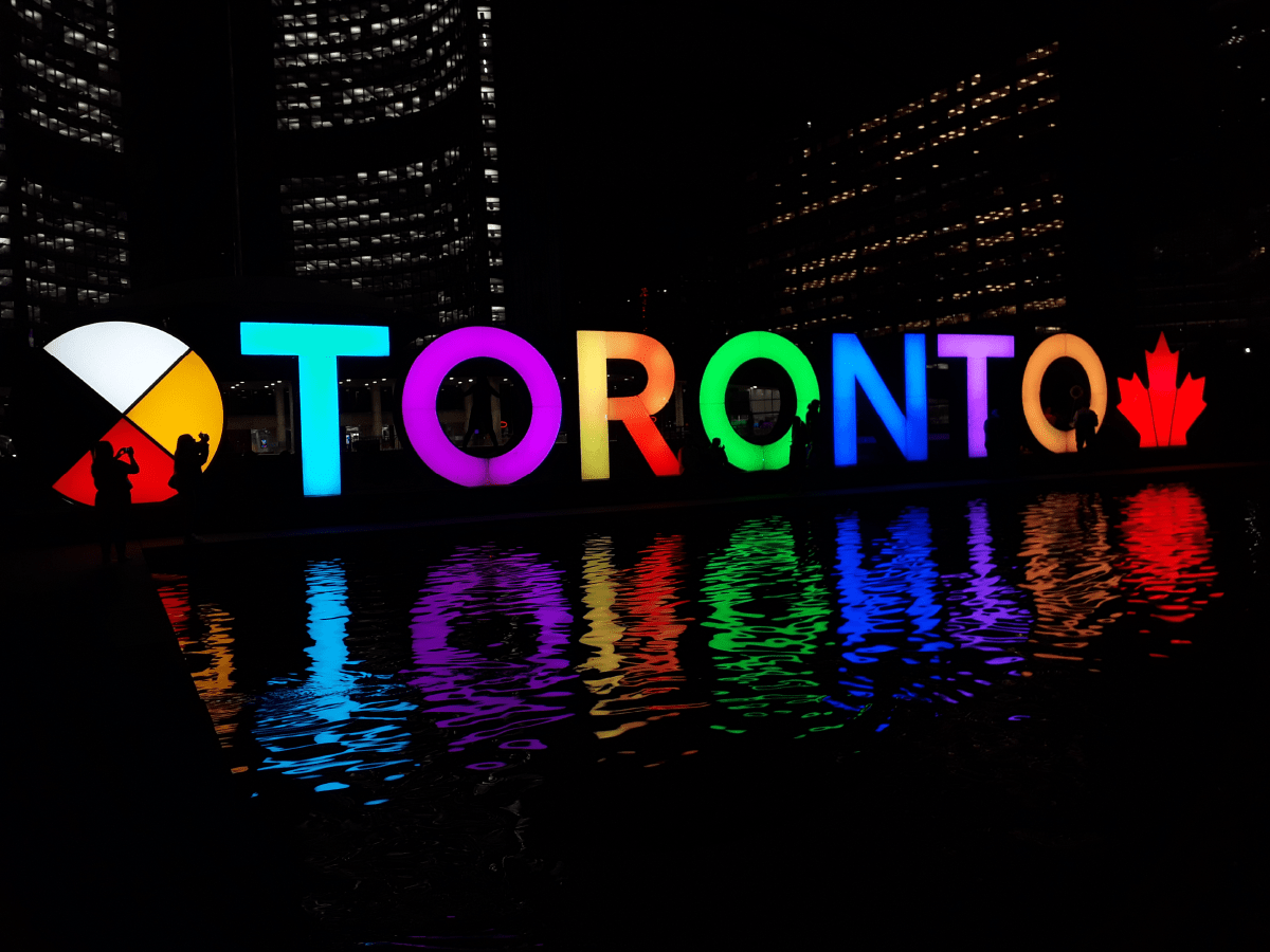Colourful Toronto sign by town hall at night-time.