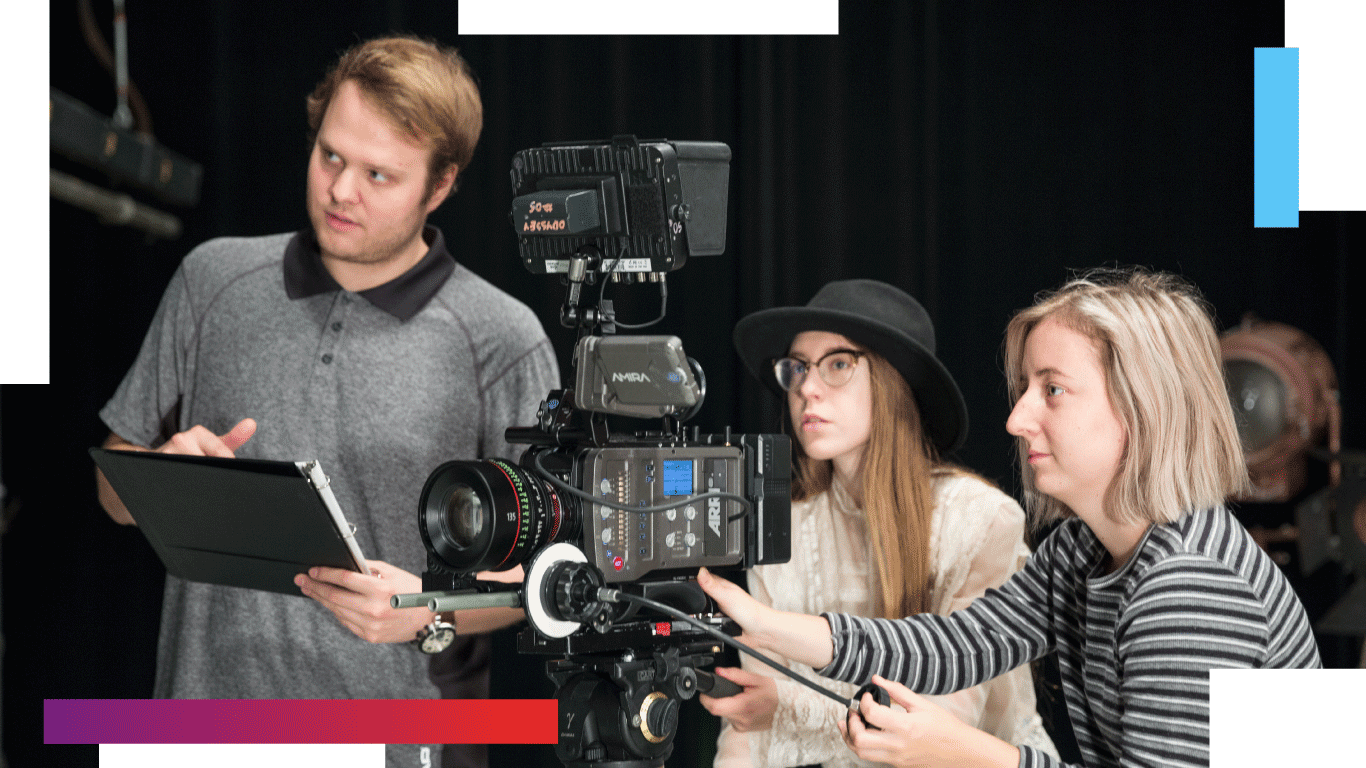 Several students on a film set gathered around a professional camera