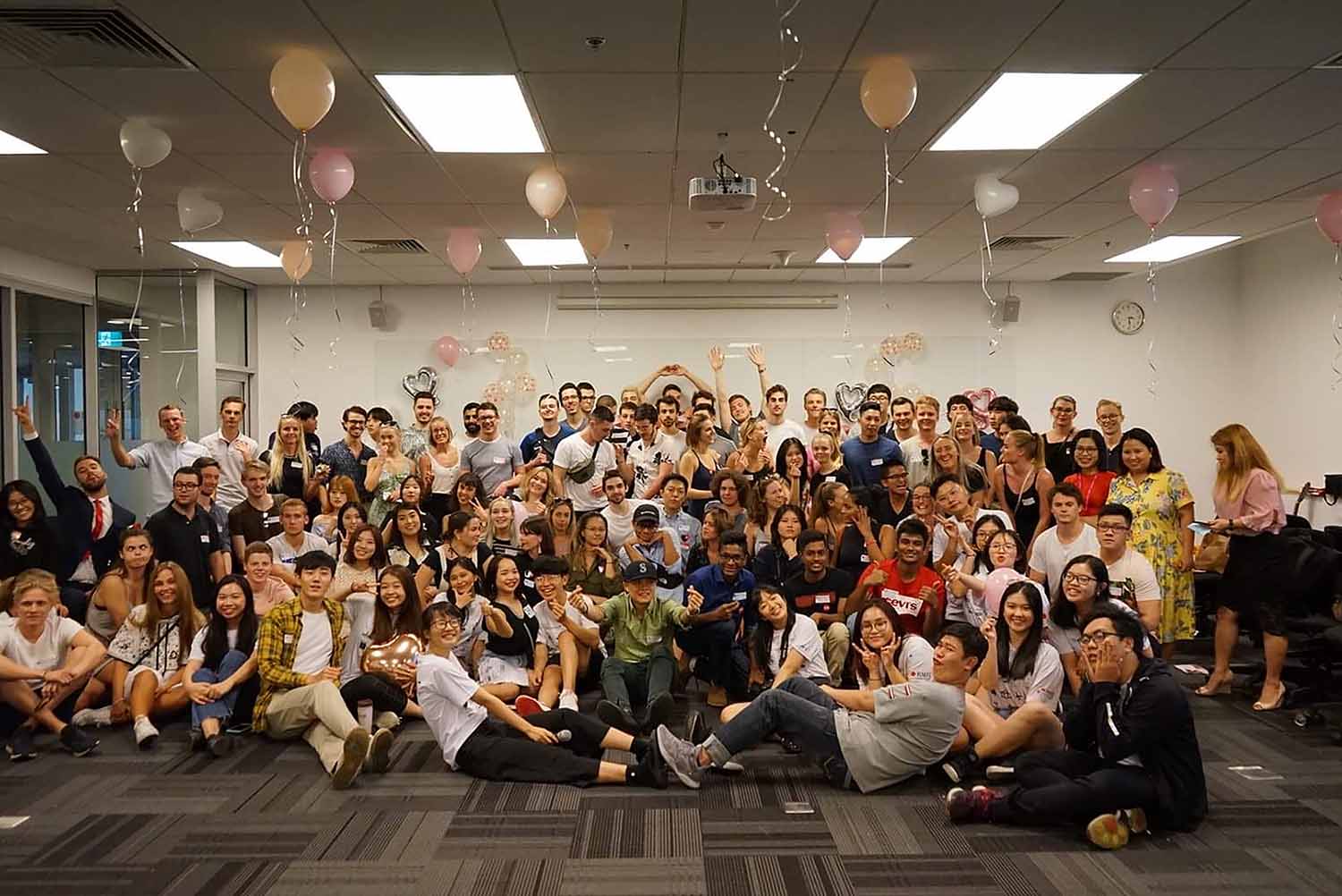 student group photo celebrating end of term with balloons in the cieling