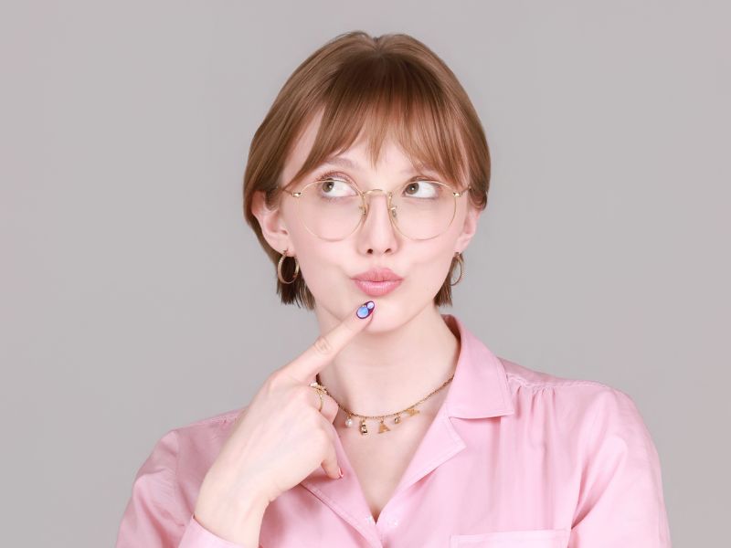 Abigail Curtis poses for a headshot, wearing a pink shirt in front of a neutral background
