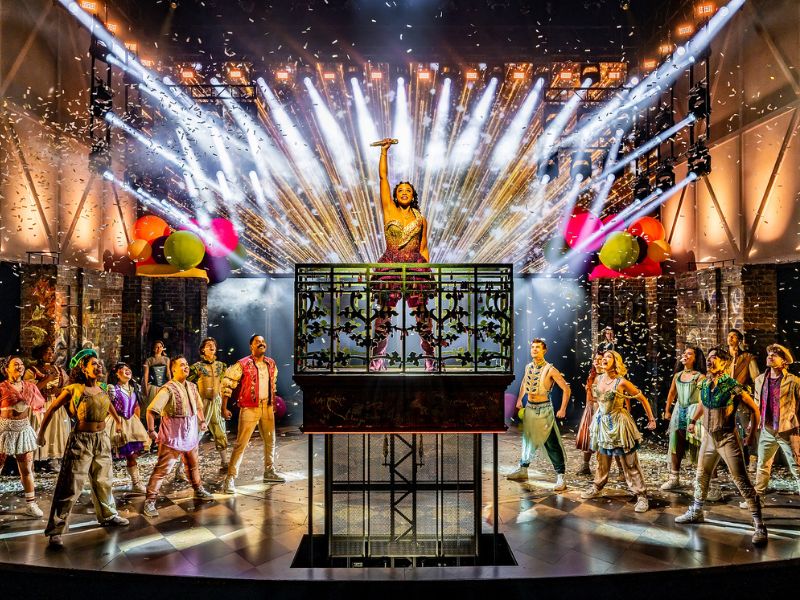 Photo of the full ensemble cast of & Juliet while performing on stage at the Royal Alexandra Theatre. Vanessa Sears plays Juliet and is centre stage pumping her fist to the air.