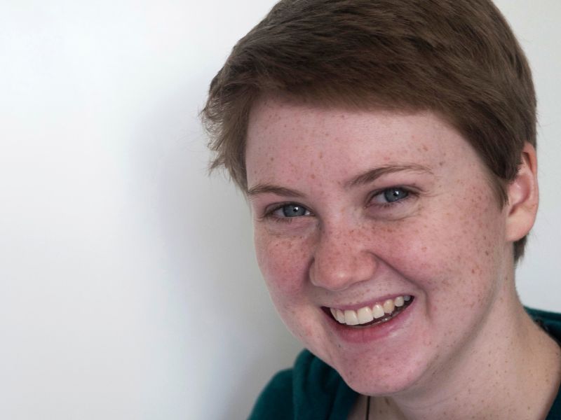 Anna Spencer is smiling for a photo in front of a white background.