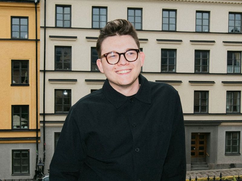 A photo of Mat Landry smiling in front of a European landscape of buildings.