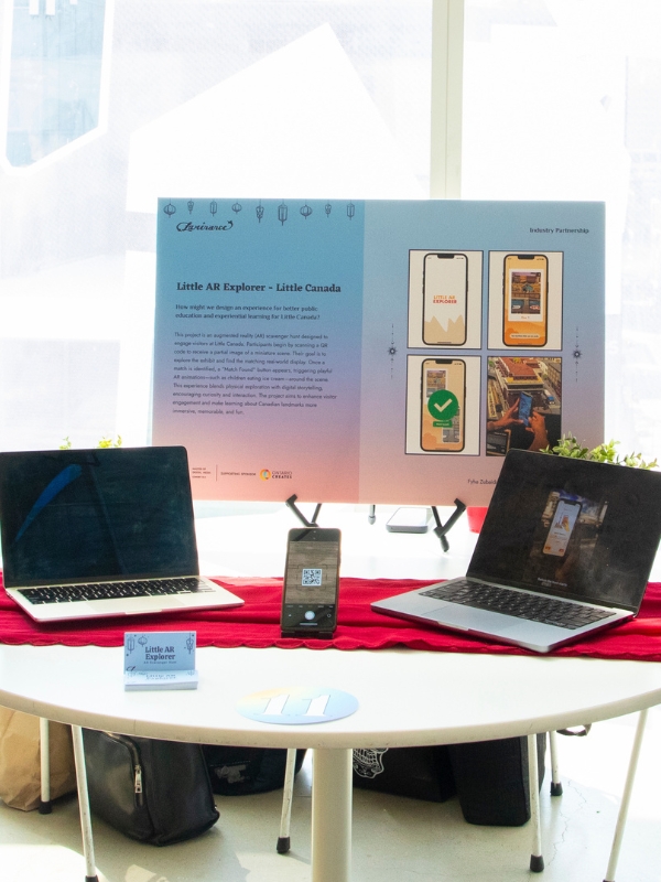 A table with a poster, two laptops, and a phone showcasing a research project.
