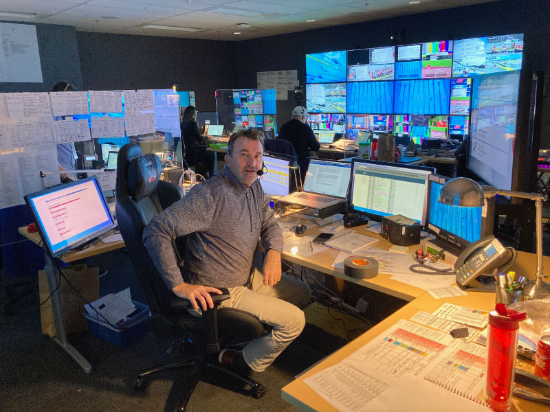 producer sits in chair behind wall of monitors