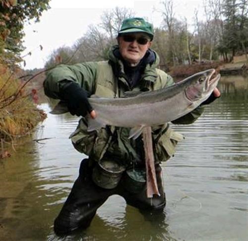 John Kitamura in a green fishing outfit holding a large fish