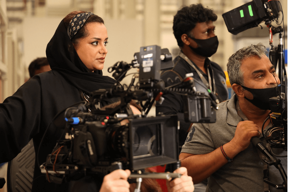 Nayla Al Khaja on set overseeing the film crew. Al Kahaja wears all black and looks at one of the cameras.