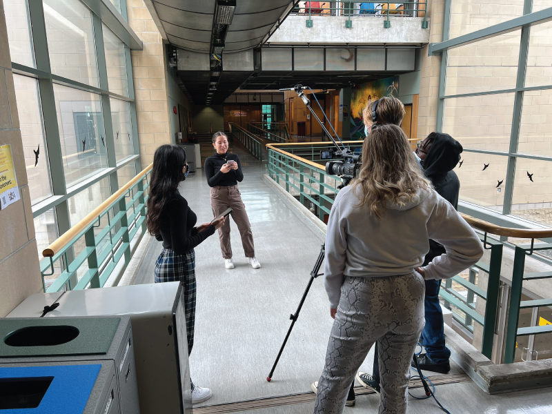 Students standing in a campus building getting ready for a TV broadcast