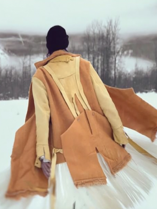 A figure wearing a yellow and orange overcoat with their back towards the camera