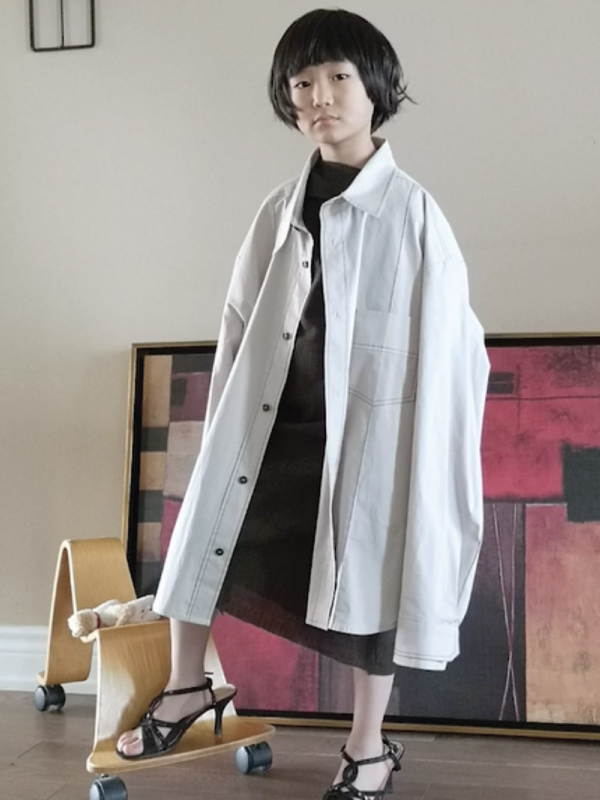 A woman wearing a black dress with an oversized white dress shirt on top and black strappy heels