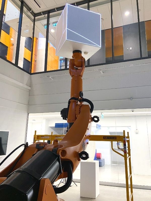 KUKA robotic arm extended upwards with a cube attachment that will serve as a screen for projected images