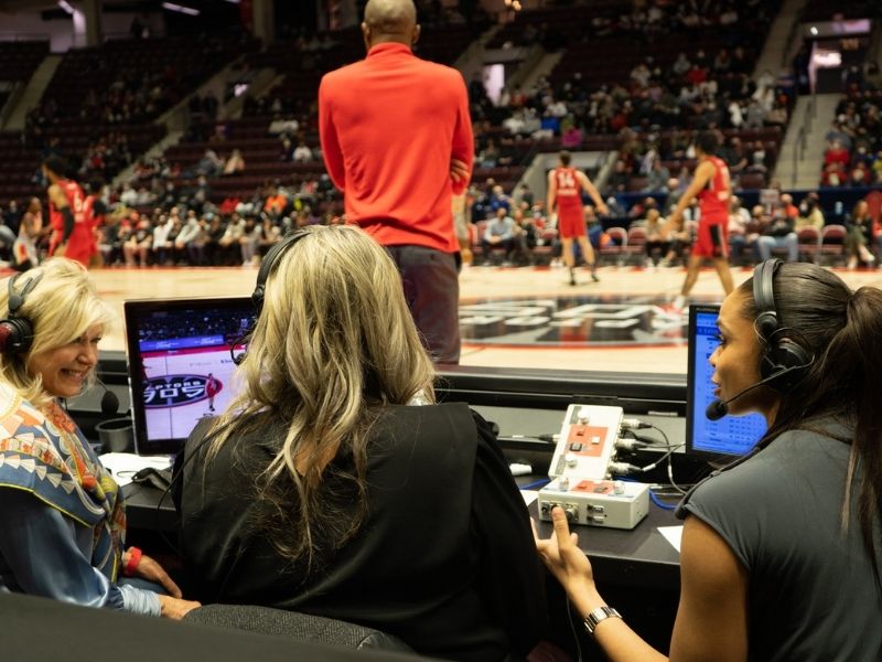 Three women commentating at a basketball game form the sidelines