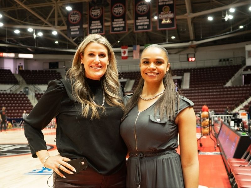 Two women standing side by side and smiling 