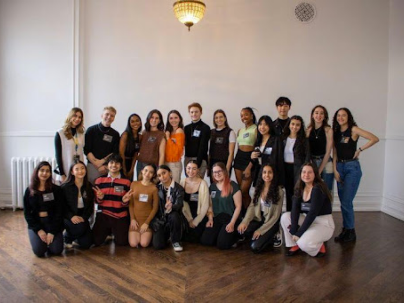 A group of people posing in front of a large white wall.