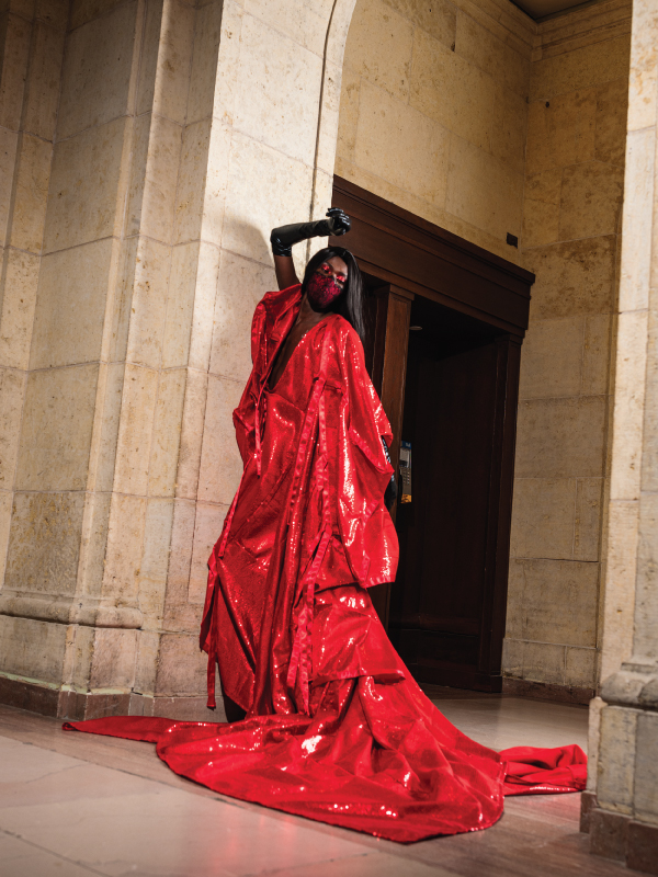 A person poses dramatically in a bright red ball gown