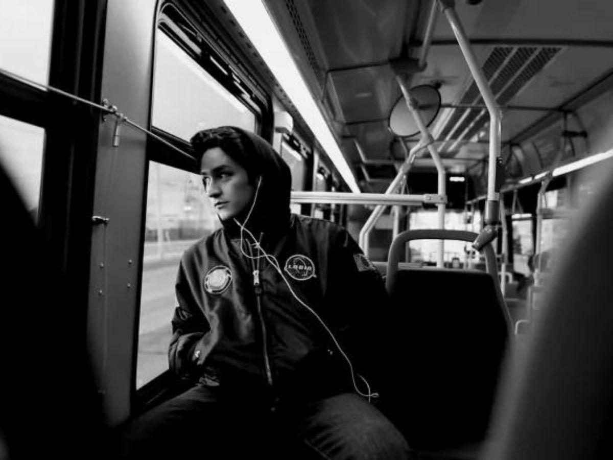 Young man seated on a TTC bus with his head resting on the window as he looks out onto the passing street. 