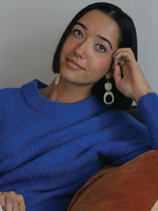 Portrait of alumni Justine Woods in a bright blue sweater and white earrings