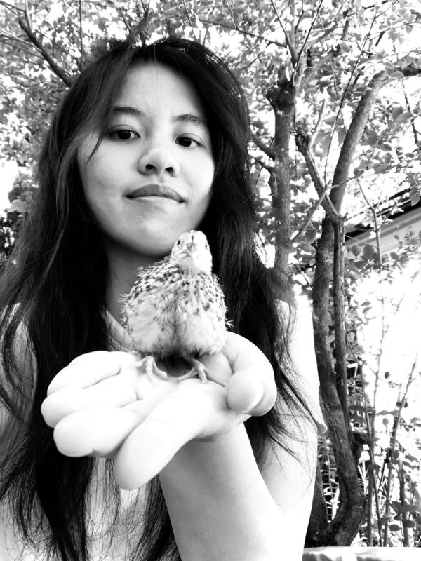 Woman holding up a chick in her palm 