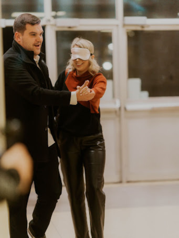 a man is leading a blinfolded woman 