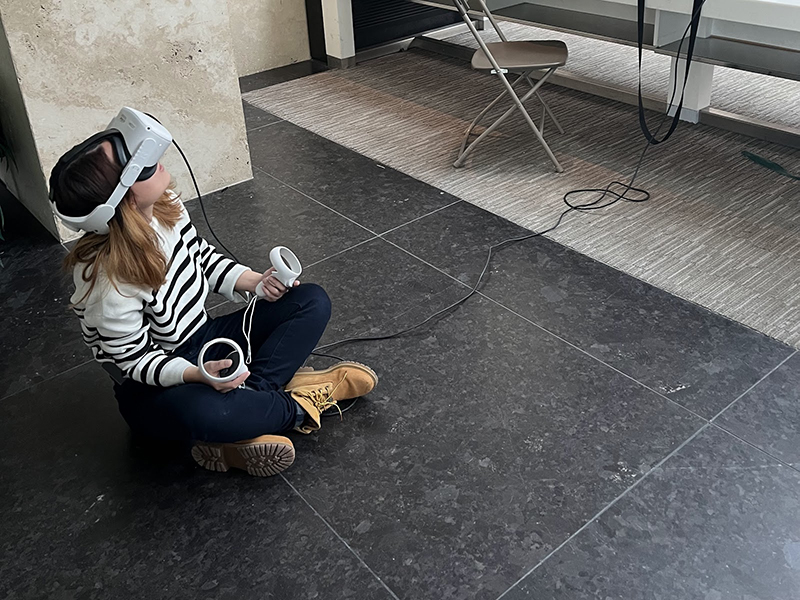 A girl sits on the floor with VR glasses on