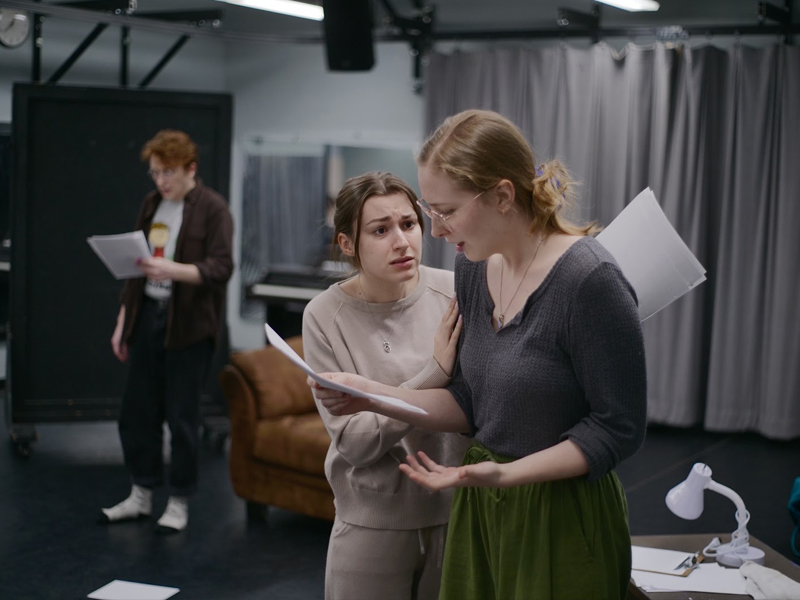 Students practicing during rehearsal with scripts in hand