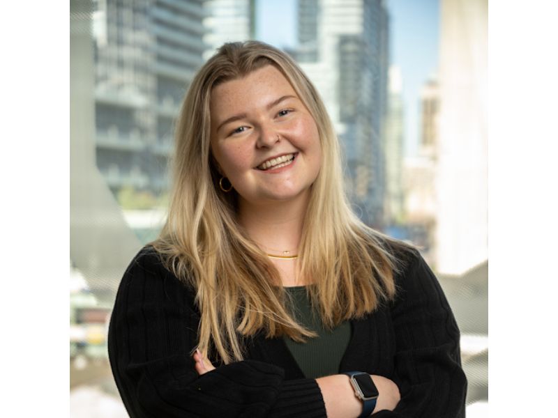 A woman standing with her arms crossed and enthusiastically smiling. 