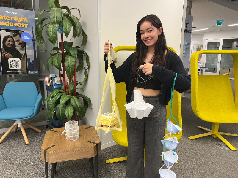 A student smiles while holding upcycled medical waste that can be used in a variety of new and reimagined ways