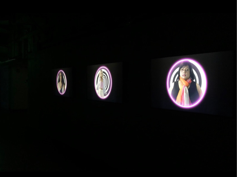 Three circles are projected on a dark wall. Each circle has a person in the center of it. 